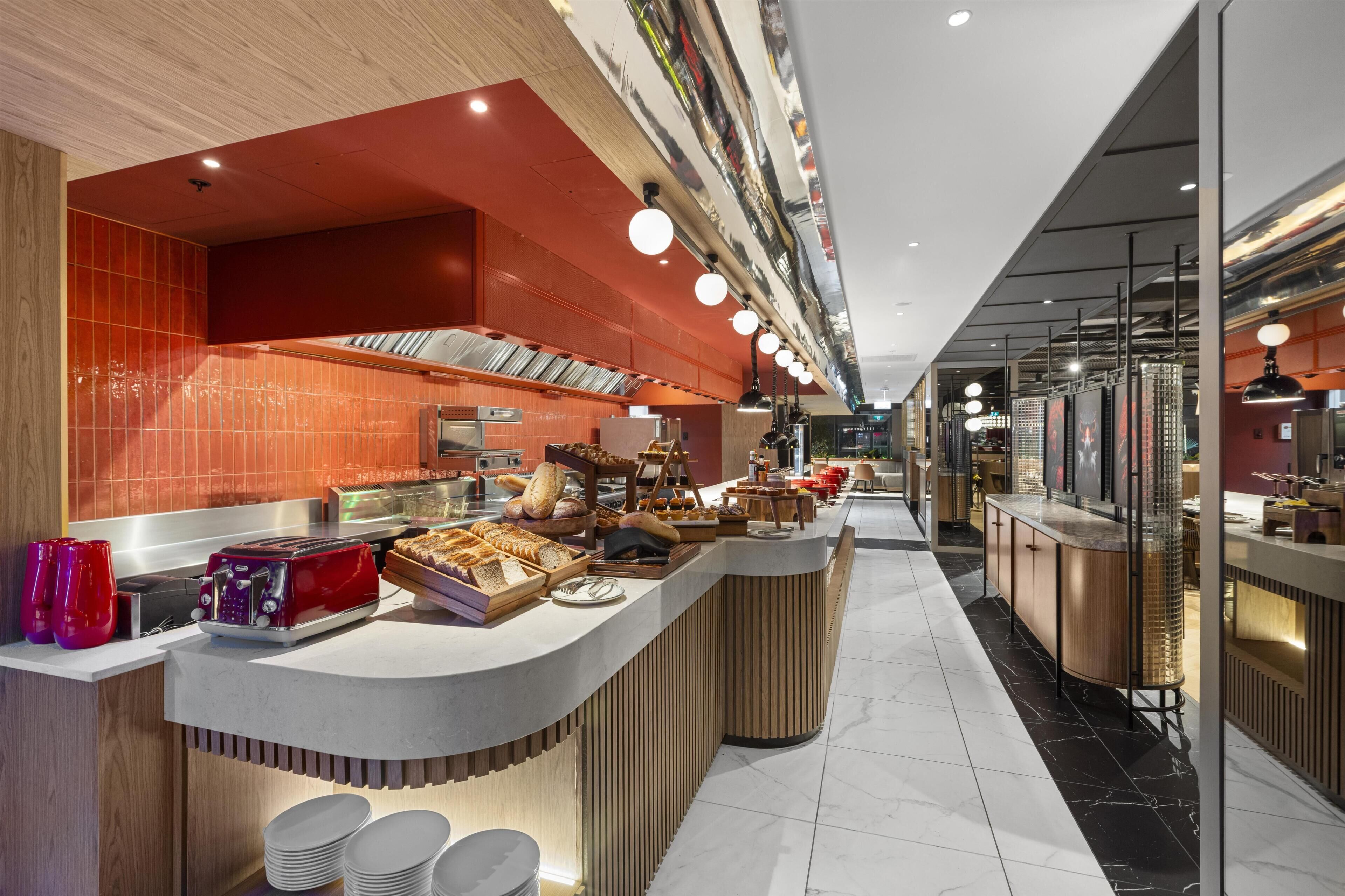 A modern kitchen area with a central counter displaying bread and pastries, a microwave, and a toaster.