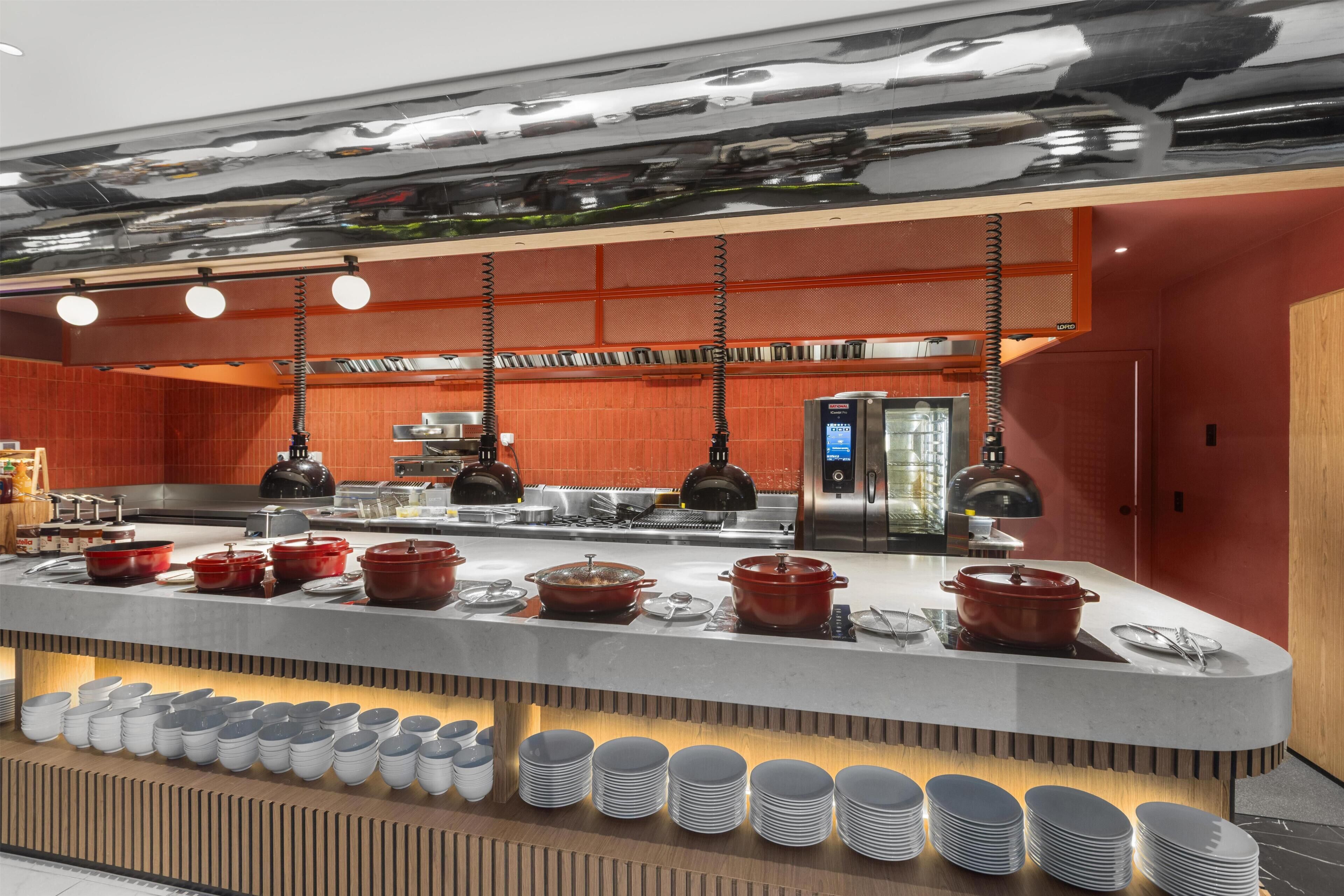 A modern kitchen with stainless steel appliances, a central island with cooking pots, and a variety of dishes and utensils.