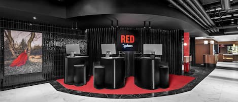 Un área de recepción moderna con una pared curva, un letrero digital grande que dice “RED Radisson” y una alfombra roja que conduce a mostradores de recepción.