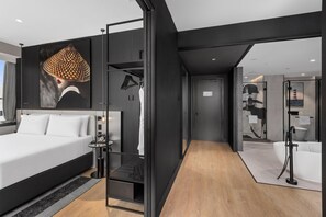 A modern hotel room with a large bed, a wardrobe, a small table, and a bathroom visible through an open door. - Radisson RED Auckland (Auckland)