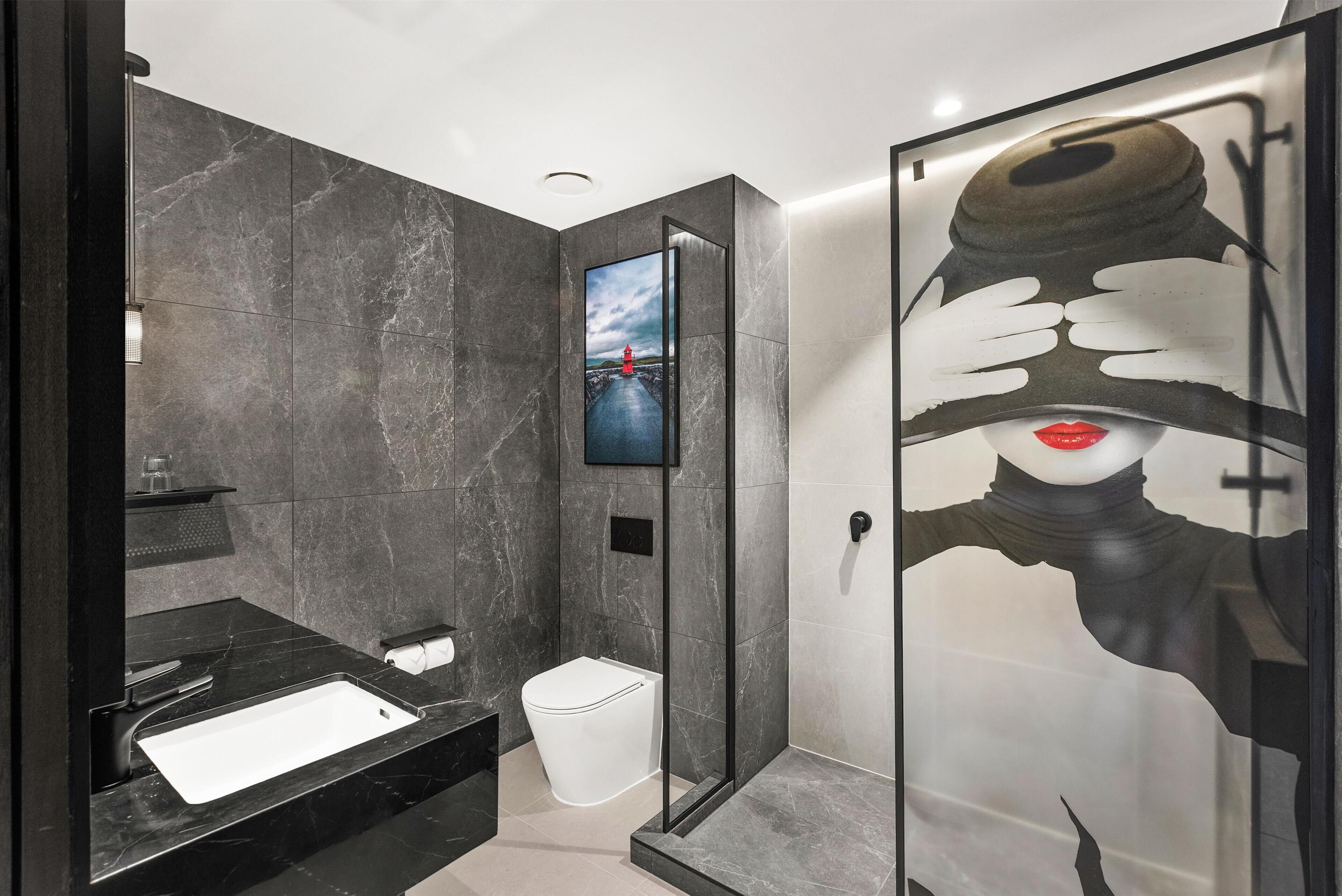 A modern bathroom with a black sink, a toilet, and a glass shower enclosure.