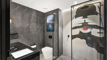 A modern bathroom with a black sink, a toilet, and a glass shower enclosure.