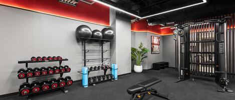 A gym with weight racks, dumbbells, a bench, and a squat rack.