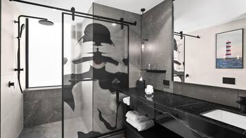A modern bathroom with a glass shower enclosure, a black marble countertop, and a large mirror.