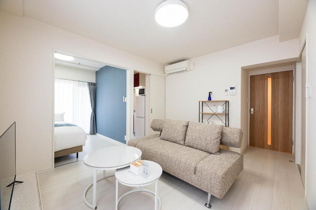 Une chambre d’hôtel comprenant un lit, un canapé, une petite table, une télévision et une porte donnant sur une autre pièce.