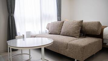Habitació moderna amb un sofà, una taula rodona i un llit.
