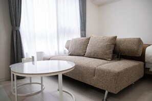 Una habitación moderna con sofá, una mesa redonda y una cama.