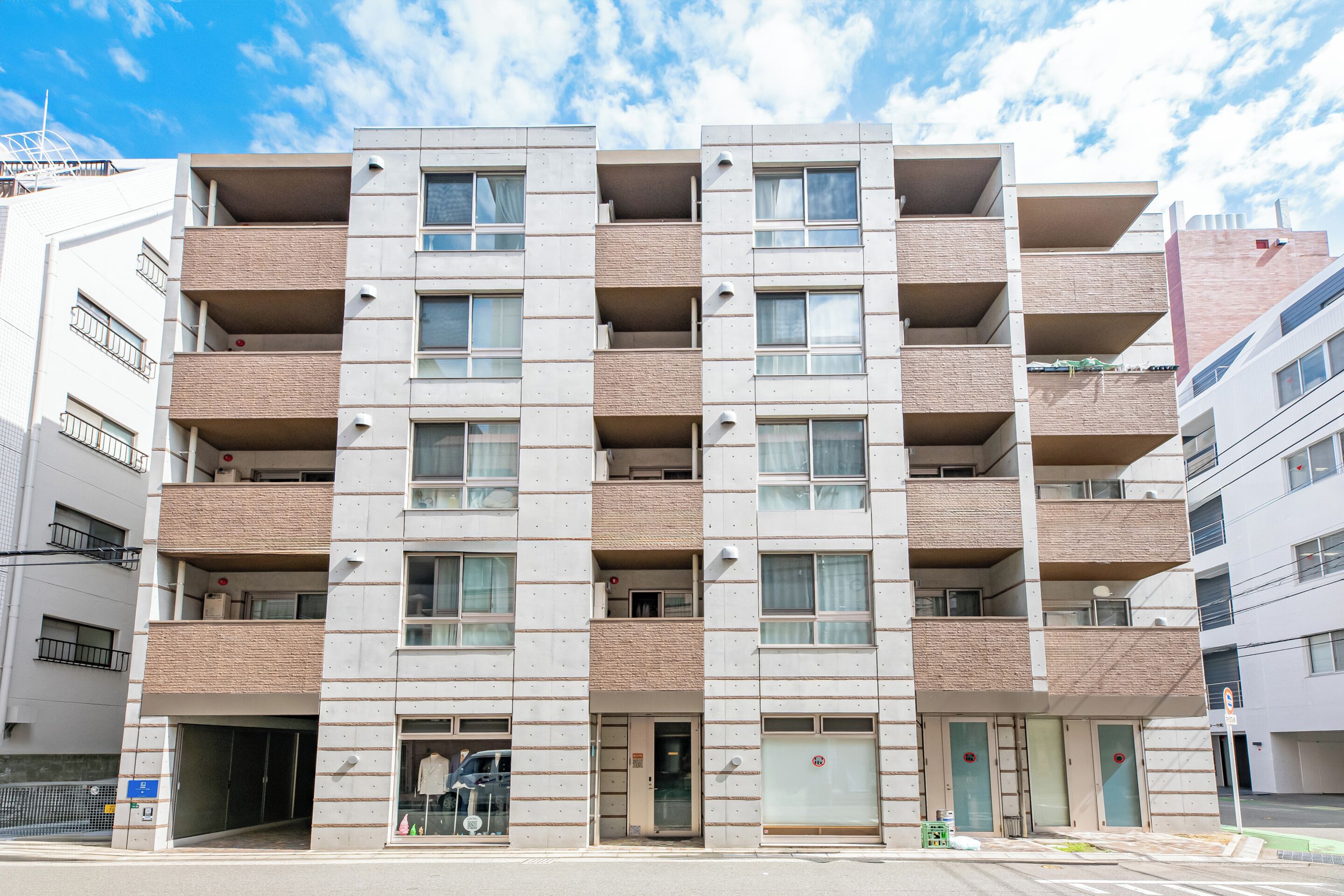 A multi-story residential building with a uniform facade, multiple balconies, and a ground-level entrance.