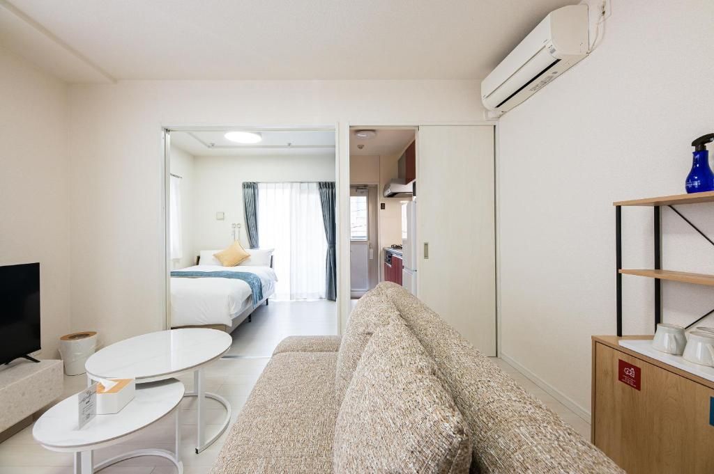 A hotel room with a sofa, a small table, a TV, and a bed with a window.