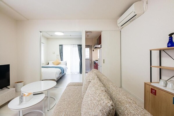 Een hotelkamer met een bank, een klein tafeltje, een televisie en een bed met raam.