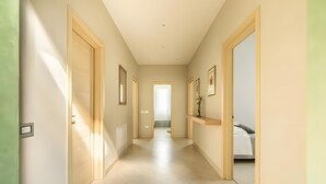 A hallway with a bed at the end, framed pictures on the walls, and a light-colored floor. - Villa Il Fico – Cavriglia: Relax in the Heart of Chianti (Cavriglia)