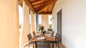 An outdoor dining area with a wooden table and chairs, a vase with flowers, and a view of greenery. - Villa Il Fico – Cavriglia: Relax in the Heart of Chianti (Cavriglia)
