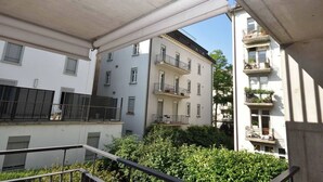 Une vue d’un immeuble résidentiel à plusieurs étages, doté de balcons, d’une fenêtre visible et d’une rambarde en métal.