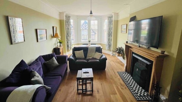 A living room with a sofa, a coffee table, a fireplace, and a TV.