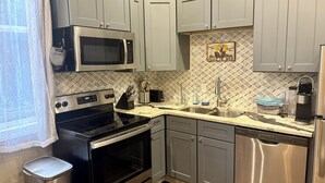A modern kitchen with grey cabinets, stainless steel appliances, and a diamond-patterned backsplash. - Cozy Louisville Gem Mins from U of L Hospital & Downtown (Louisville)