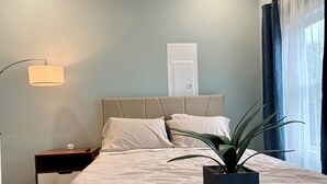 A neatly arranged bedroom with a bed, bedside table, lamp, and a potted plant. - Cozy Louisville Gem Mins from U of L Hospital & Downtown (Louisville)