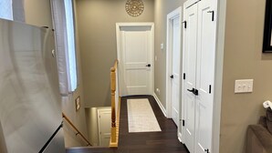 A hallway with a wooden floor, white doors, a white refrigerator, and a small rug. - Cozy Louisville Gem Mins from U of L Hospital & Downtown (Louisville)