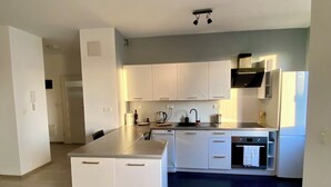 Een moderne keuken met witte kasten, een zwart aanrecht en een inbouwoven.
