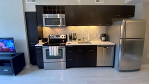 A modern kitchen with dark cabinets, stainless steel appliances, a microwave, oven, and a refrigerator. - 1-bedroom in Arlington, DC metro area with on-site parking included (Arlington)