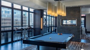 A pool table in a modern room with large windows, a bar area, and a fireplace. - 1-bedroom in Arlington, DC metro area with on-site parking included (Arlington)