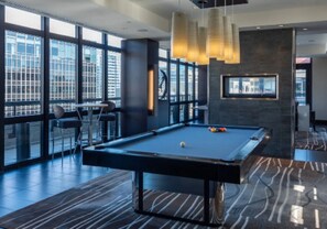 Een pooltafel in een moderne ruimte met grote ramen, een bar en een open haard.