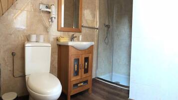 A bathroom with a toilet, sink, mirror, and shower.