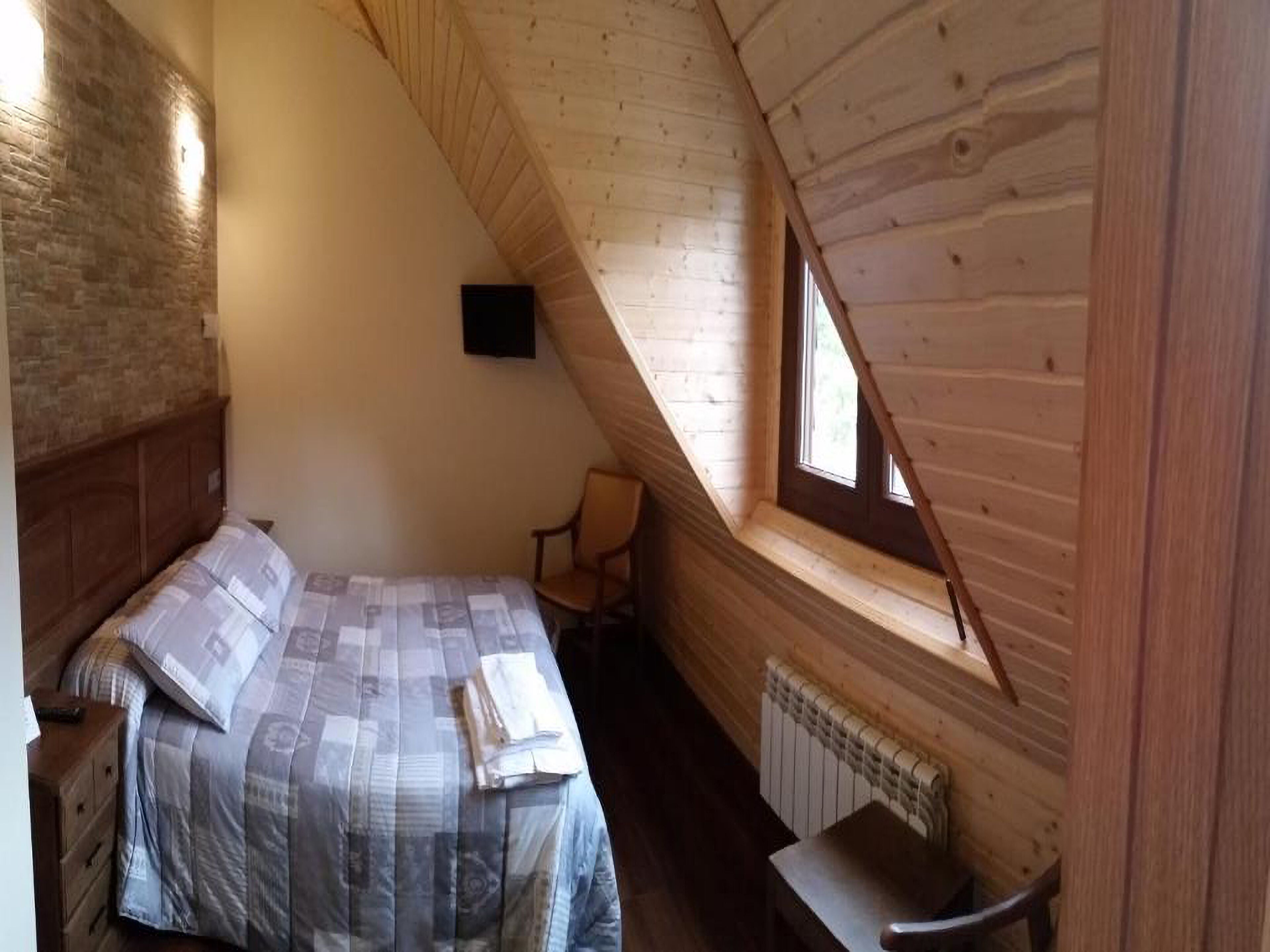 A bedroom with a bed, a chair, a radiator, and a window.