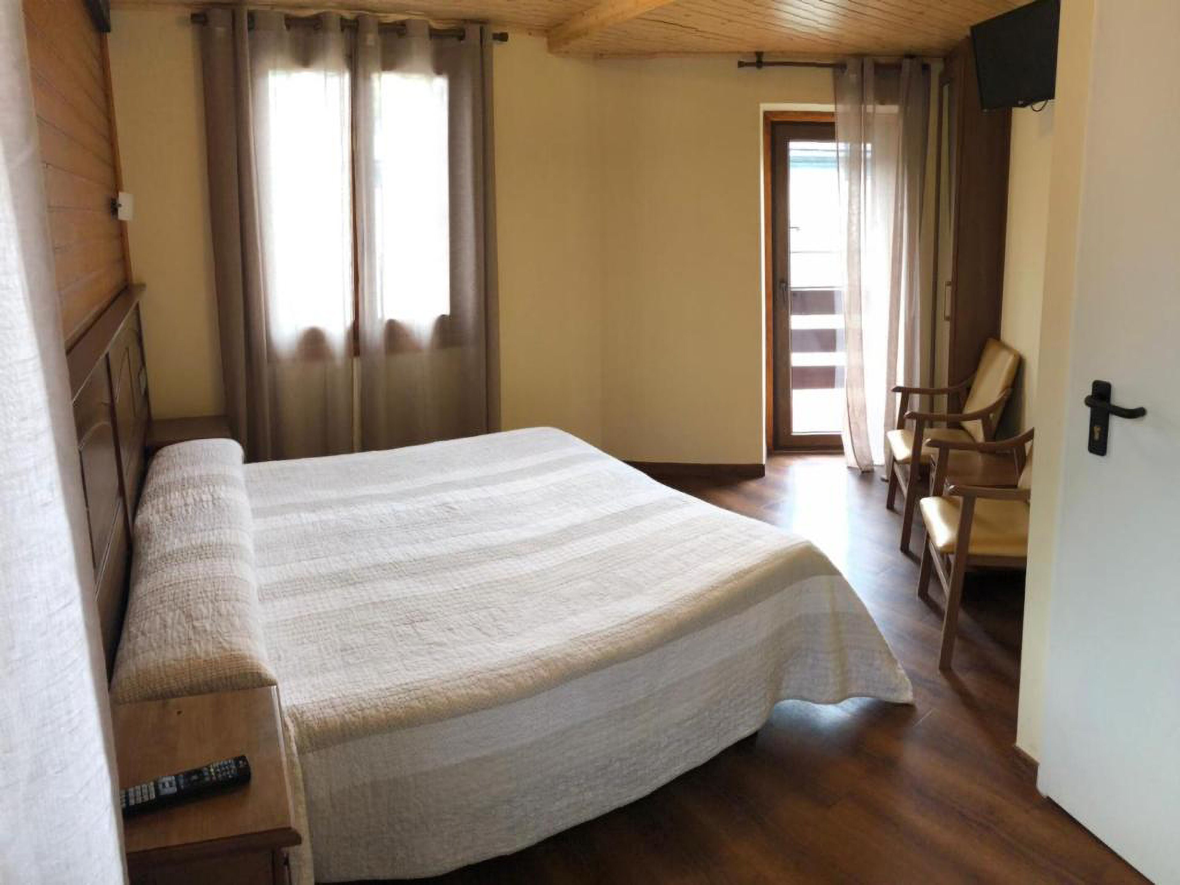 Ein Schlafzimmer mit einem großen Bett, einem Holz-Kopfteil und einem an der Wand befestigten Fernseher.