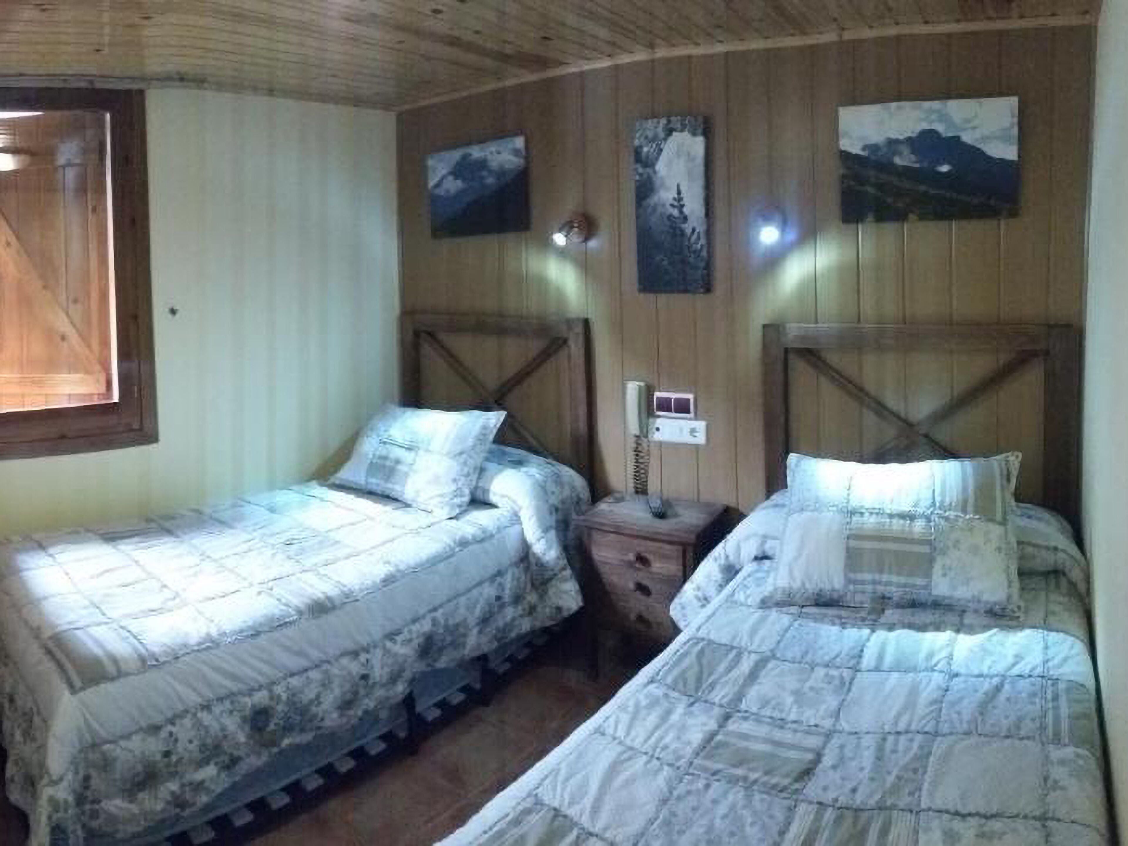 Una habitación con dos camas, paredes de madera y una ventana.