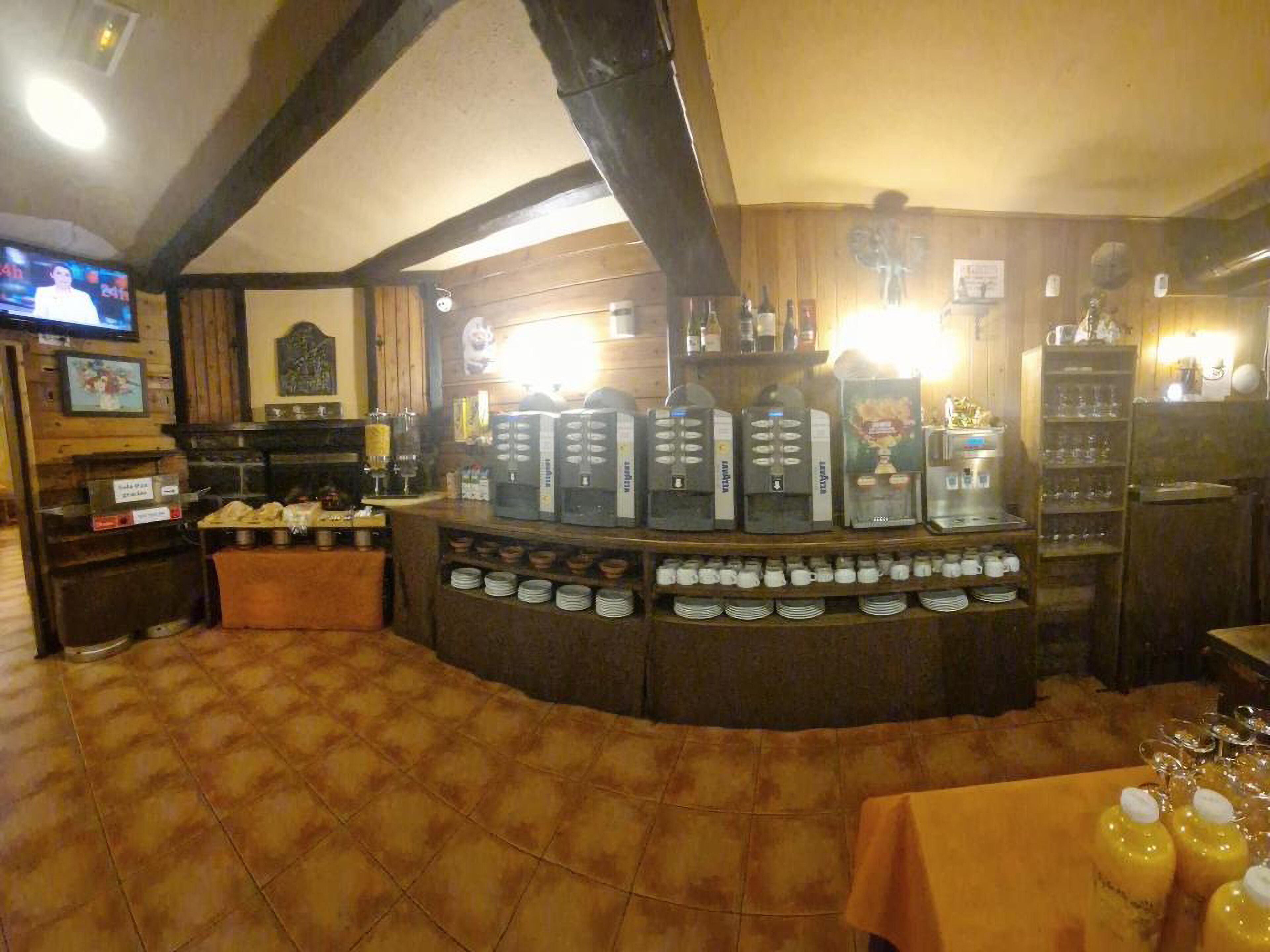 Eine Bar mit einer Kaffeestation, Regalen voller Flaschen und einem Fernsehbildschirm.