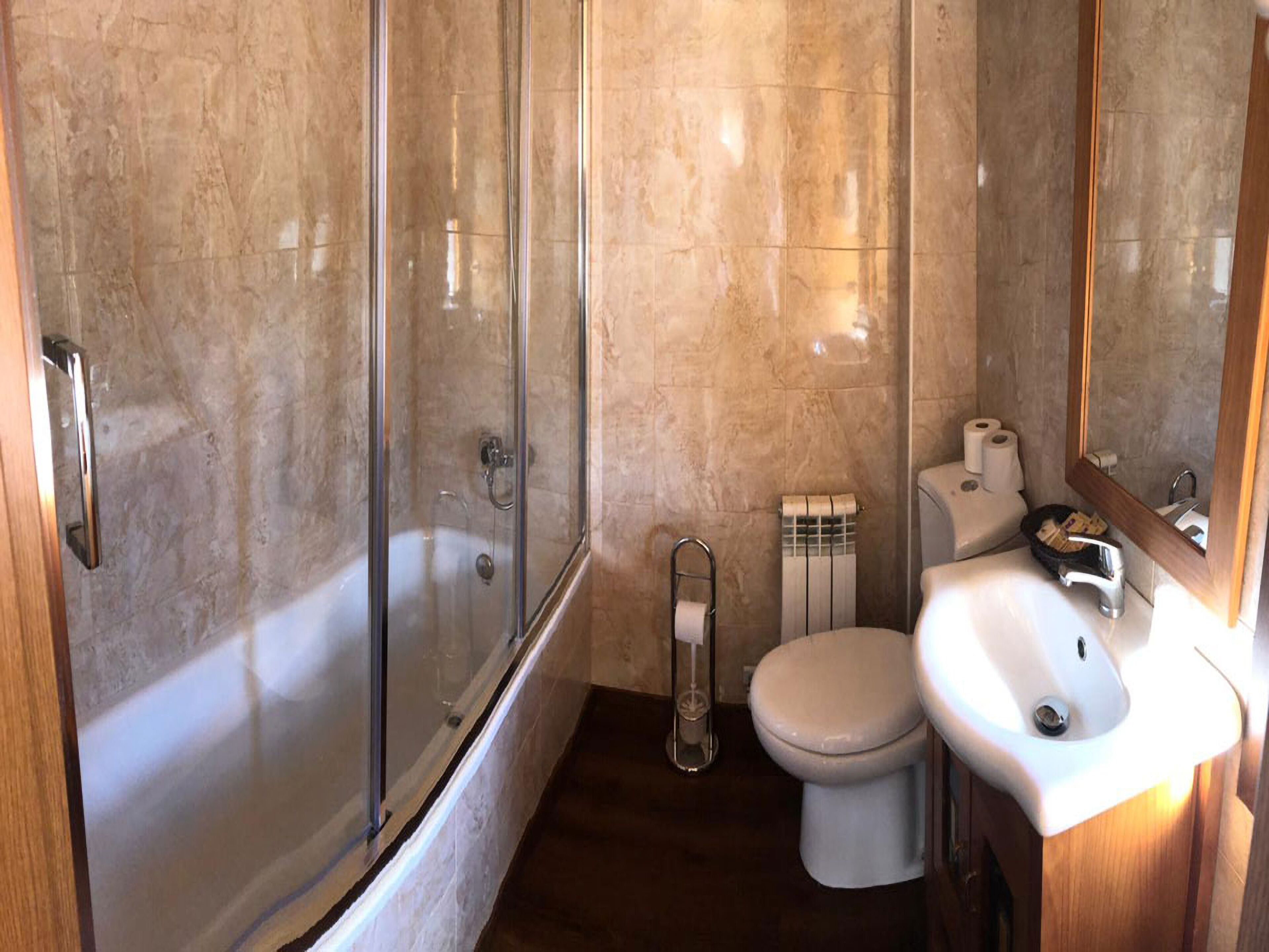 Une salle de bain avec une douche à parois de verre, des toilettes et un lavabo avec un miroir.