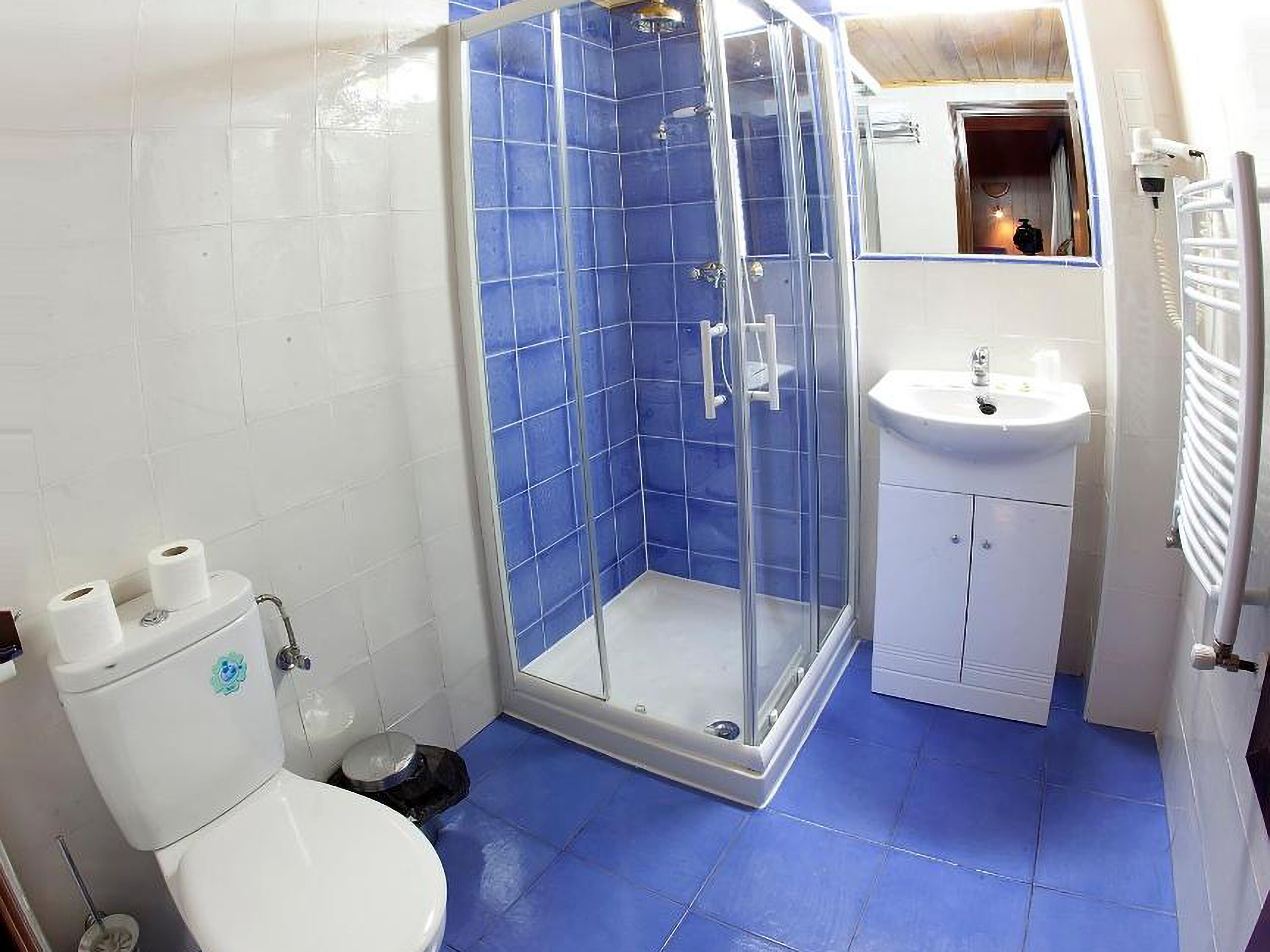 Un baño con ducha de vidrio, un lavabo blanco y un inodoro.