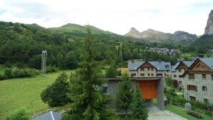 A mountain village with traditional stone buildings, a prominent wooden structure, and a lush green landscape. - Hotel Sarao 3000 (Escarrilla)
