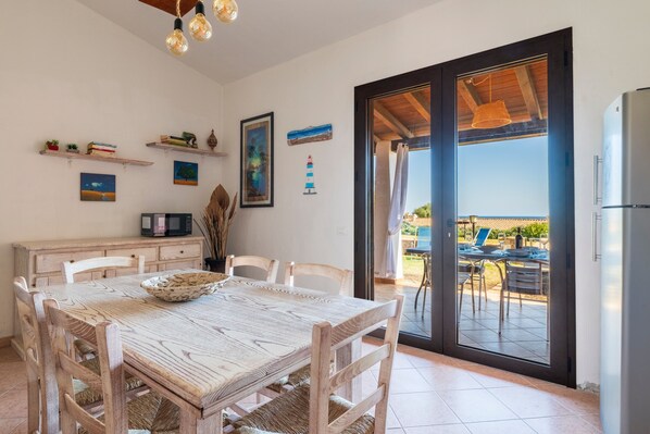 Un comedor con una mesa y sillas de madera, un refrigerador y vistas del patio exterior.