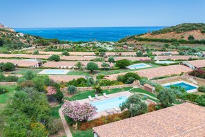 Un complejo turístico frente al mar con varias piscinas, jardines exuberantes y edificios escalonados.