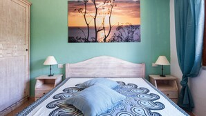 A bedroom with a bed, two bedside tables, a nightstand, a wardrobe, and a wall-mounted picture. - Villa 'Casa Joy' with Sea View, Wi-Fi and Air Conditioning (Tertenia)