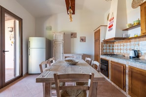 Une cuisine équipée d’une table à manger, de chaises, d’un réfrigérateur, de placards et d’un pare-feu en carreaux.