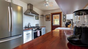 Une cuisine moderne dotée d’appareils électroménagers en acier inoxydable, d’un plan de travail en bois et d’un ventilateur de plafond.