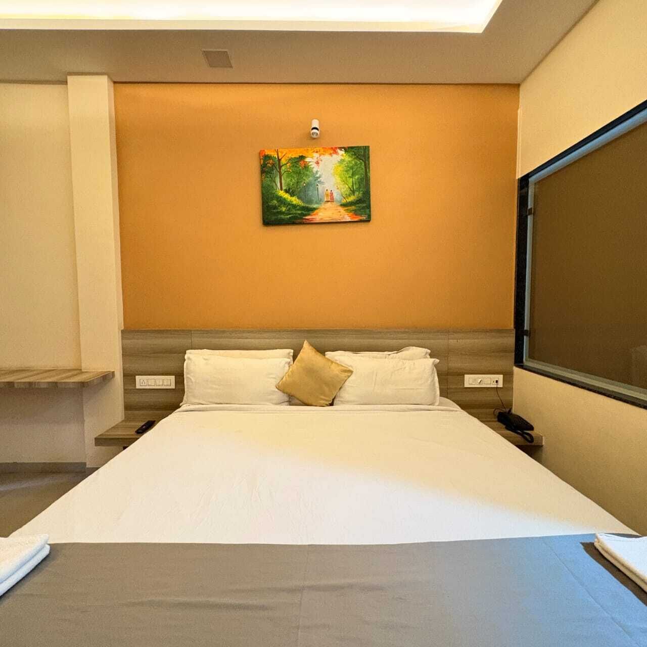 Une chambre d’hôtel avec un lit, un tableau au mur et une grande fenêtre.