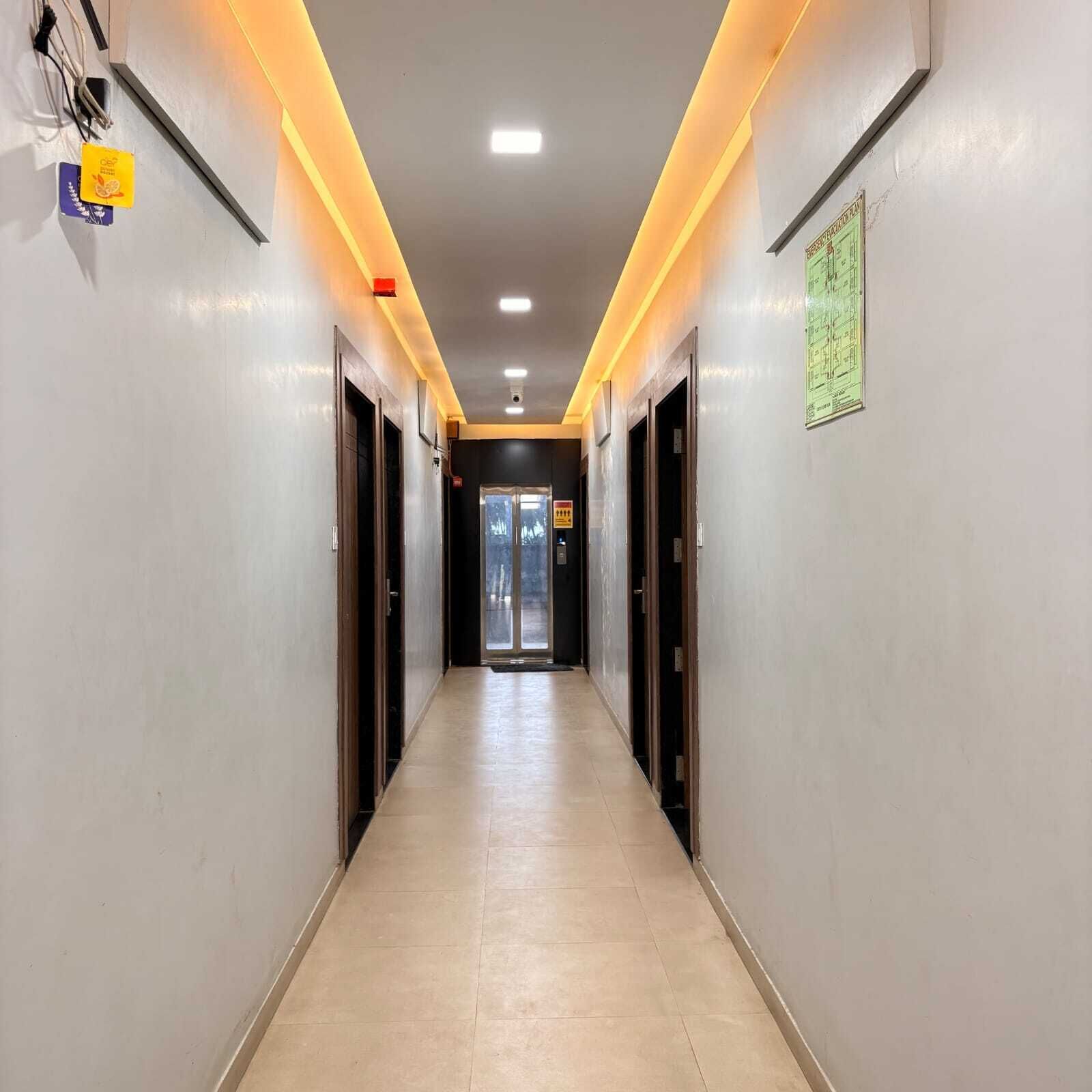 Un couloir d’hôtel moderne avec un sol carrelé, un éclairage encastré et des portes des deux côtés.