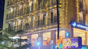A multi-story hotel with balconies, a visible restaurant named "Cafe Beat," and a neon sign for "Avon." - Avron Beach Resort (Daman)