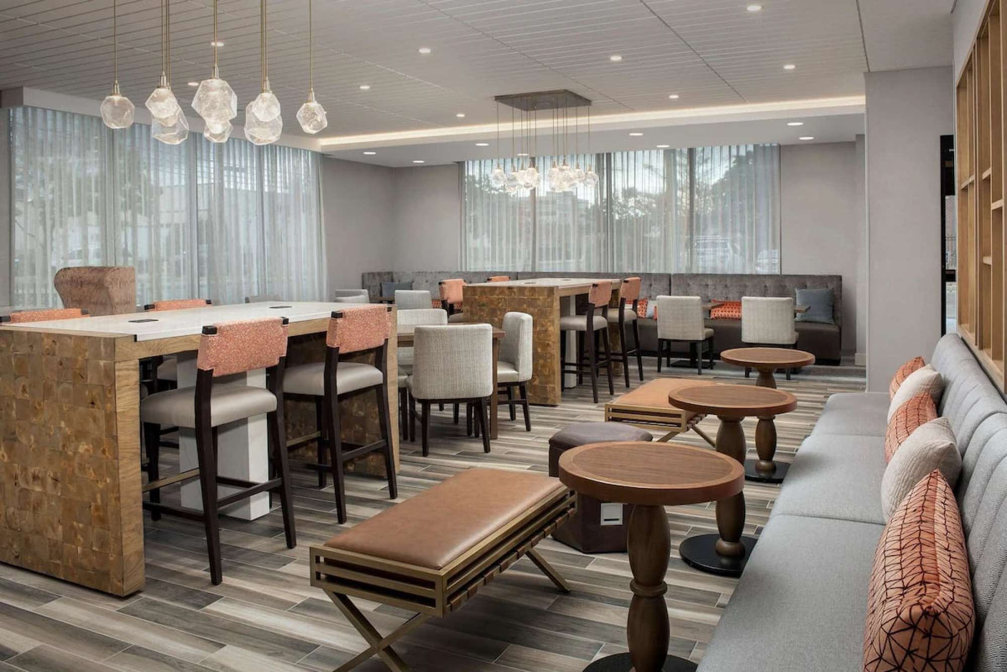 A modern hotel lobby with a bar area, seating arrangements, and large windows.