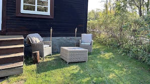 Une cabane en bois avec deux fauteuils en osier et une petite table à l’extérieur.