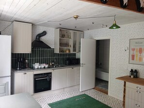 Una cocina con armarios blancos, estufa negra y salpicadero con diseño verde.