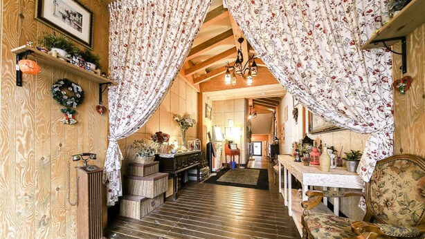 Una habitación acogedora con pisos de madera, un teléfono antiguo, una chimenea y un sillón floral.
