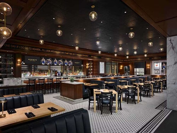 Zona de bar con diversas opciones de asientos, incluyendo cabinas y mesas, y una barra con una variedad de botellas.