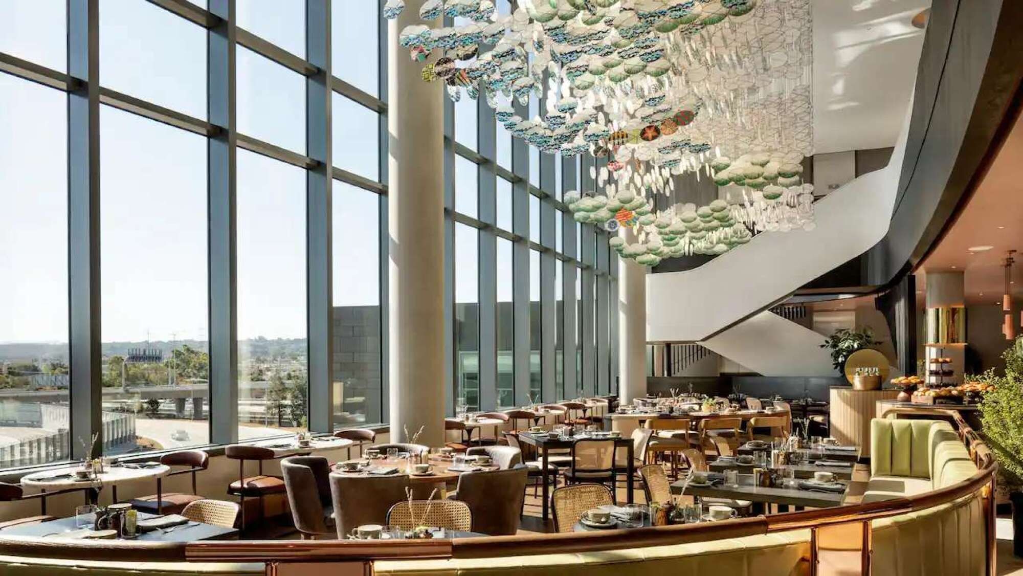 A modern hotel lobby with a high ceiling, large windows, and a unique hanging decoration.