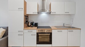 Een moderne keuken met witte kasten, een roestvrijstalen afzuigkap, een inbouwoven en een houten aanrecht.