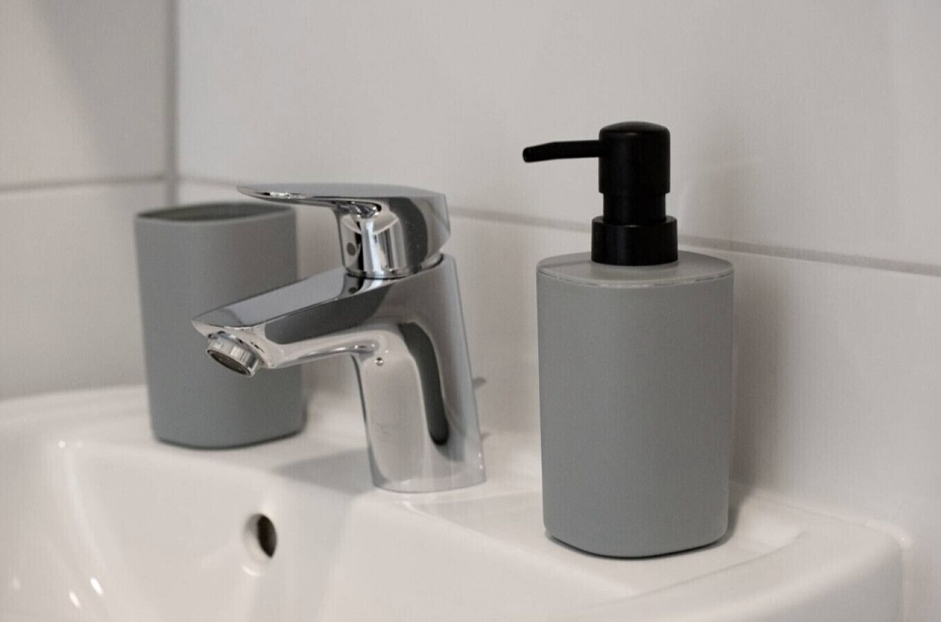 A bathroom sink with a chrome faucet and a grey soap dispenser.