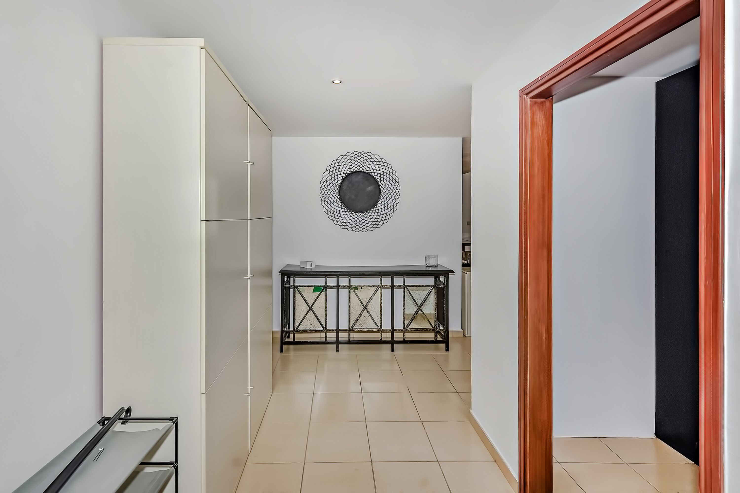 A modern kitchen with a black and white geometric wall art, a wooden-framed door, and a tiled floor.